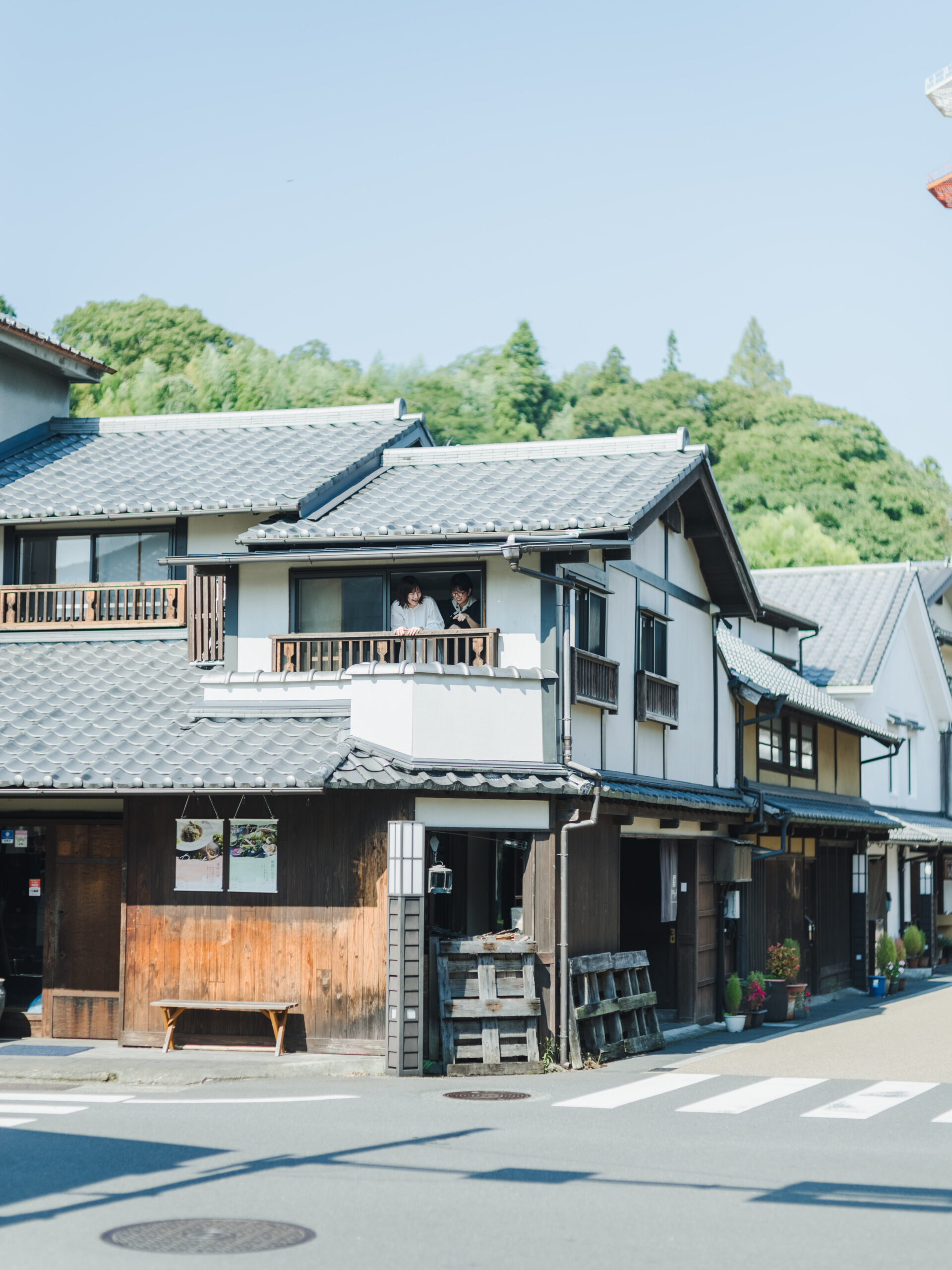 城下町角の家の窓から顔をだす二人